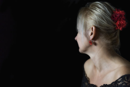 Portrait of blond middle aged woman looking from a camera on a black background. Free place for your text is in the left side of the photo. 