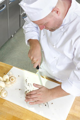 Professional chef preparing mushrooms in large kitchen