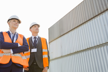 Low angle view of workers standing against cargo containers