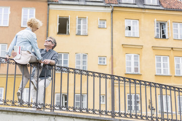 Low angle view of loving middle-aged couple by railing against building