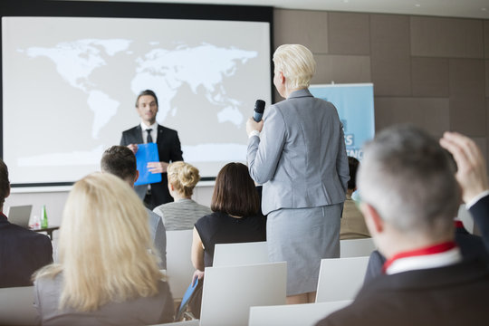 Rear view of businesswoman answering questions during seminar