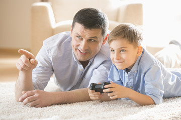 Father and son playing video game on floor at home