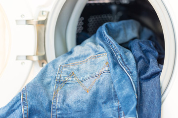 Open door in washing mashine with jeans inside
