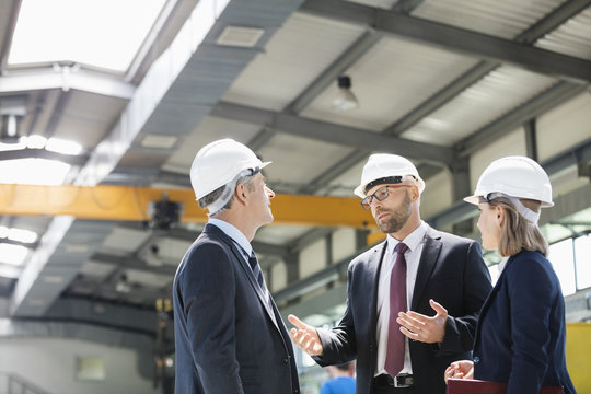 Business people wearing hardhats having discussion in metal industry