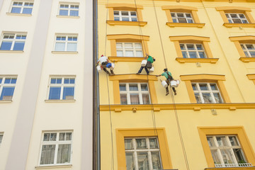 Low angle view of window washers hanging outside building