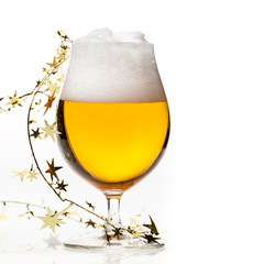 Full snifter glass of pale lager of pilsner beer with a large head of foam and golden christmas tinsel on white background - obrazy, fototapety, plakaty