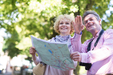 Naklejka premium Happy middle-aged couple holding map in city