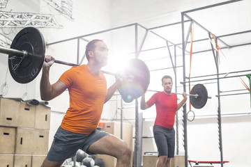 Fototapeta na wymiar Men lifting barbells in crossfit gym