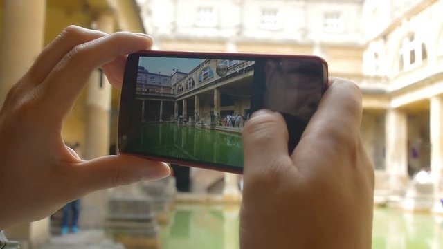 young woman making photos with a smartphone inside a museum, archeological area
