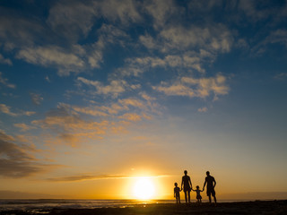 Fototapeta na wymiar Family at sunset by the ocean. People hold hands and look at the