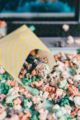 Colorful rainbow candy popcorn. Fruit flavored popcorn in yellow paper bag. Sugared popcorn texture