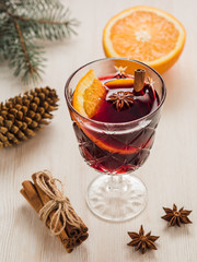 A glass of mulled wine with cinnamon, orange, anise on white woo