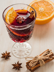 A glass of mulled wine with cinnamon, orange, anise on white woo