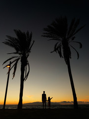 Mother and son at sunset by the ocean. People hold hands and loo