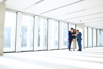 Fototapeta premium Full length of business people using digital tablet in empty office