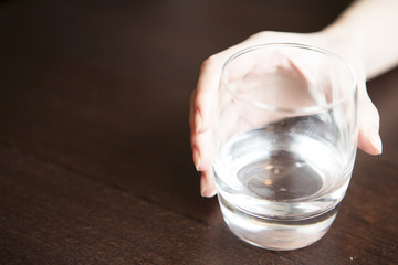 Woman's hand holding glass of water on table