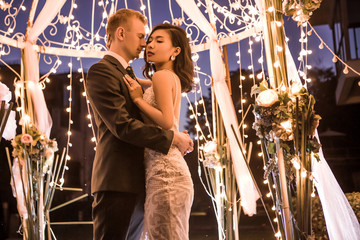 Romantic couple embracing in illuminated gazebo at night