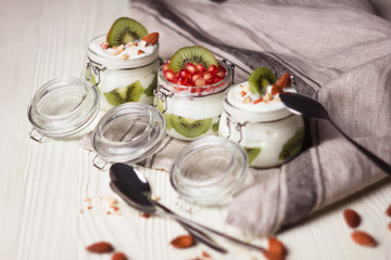 Homemade Yogurt with kiwi, garnet grains and almond on wooden table. Healthy morning meal