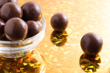 Round chocolate candy in small glass cup on colorful background