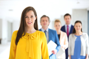Obraz premium Portrait of smiling young businesswoman with team in background at office