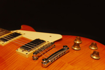Fototapeta na wymiar Honey sunburst electric guitar closeup on the black background. Shallow depth of field.