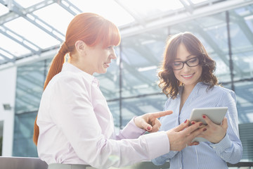 Fototapeta premium Businesswoman showing something on tablet PC to colleague in office
