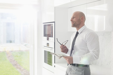 Fototapeta premium Thoughtful businessman holding newspaper at home