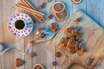 christmas background with gingerbread on wooden board and cup of coffee, baking ingredients with gingerbread