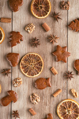 gingerbread with baking ingredients like cinnamon, orange slices and star anise on wooden background, christmas background