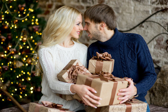 Happy couple of lovers in pullovers give each other gifts