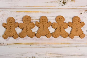 Fotobehang Christmas smiling  gingerbread men on rustic wooden background © barmalini
