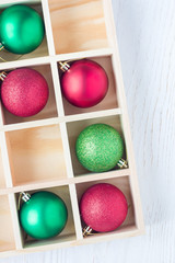 Preparation for Christmas: festive balls and candy cane in wooden box on white wooden table, vertical, copy space