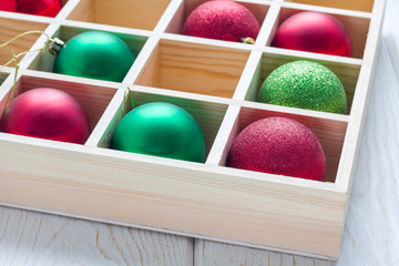 Preparation for Christmas: festive balls in wooden box on white wooden table, horizontal