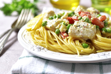 Codfish in a cream sauce with vegetables garnished with spaghett
