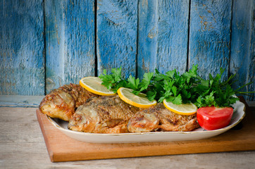 Fried fish with lemon and parsley on a blue wooden background