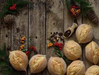 Bread bun on wooden table decorated with tree branches pine cones