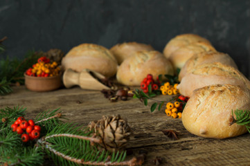 Bread bun on wooden table decorated with tree branches pine cones