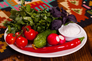 Composition of fresh vegetables and greens on a white plate
