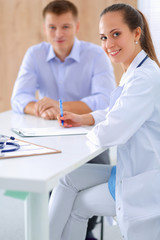 Doctor woman sitting with male patient at the desk