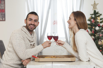 Young couple sharing a pizza for New Years eve. Christmas dinner