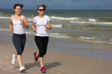 Two women running on beach 