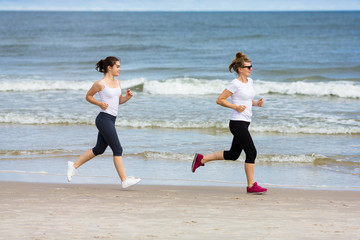 Two women running on beach 