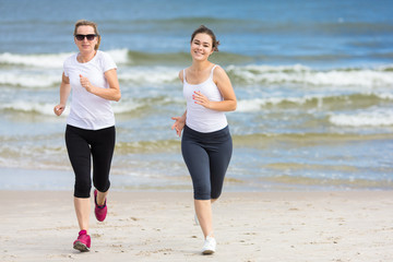 Two women running on beach 