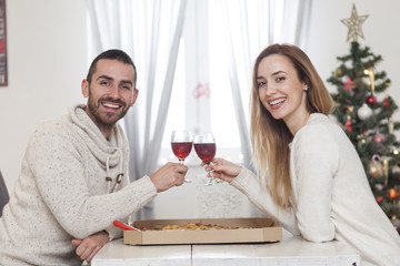 Young couple sharing a pizza for New Years eve. Christmas dinner