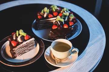 Piece of chocolate cake with cup of tee and fresh berry on black background