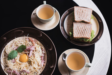 Classic Pasta carbonara  with bacon and egg yolk, egg and Parmesan with two cups of tea and desserts.
