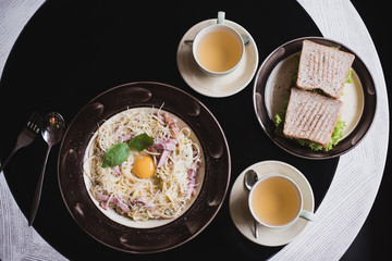 Classic Pasta carbonara  with bacon and egg yolk, egg and Parmesan with two cups of tea and desserts.