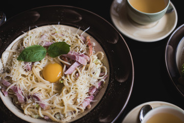 Classic Pasta carbonara  with bacon and egg yolk, egg and Parmesan with two cups of tea and desserts.