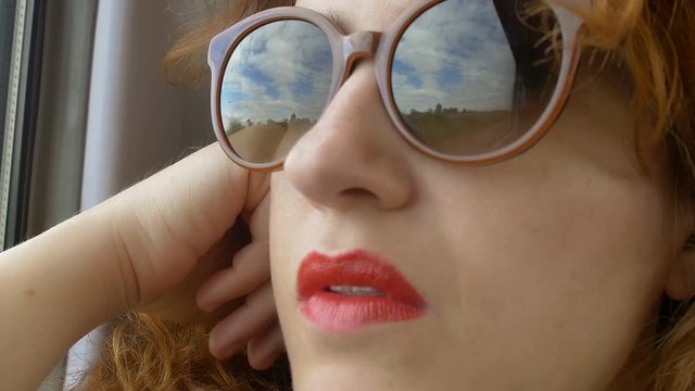 closeup footage of young woman near the window of a train and wearing sunglasses