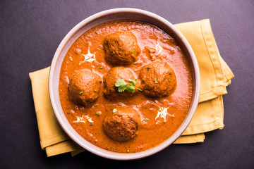 malai kofta curry - classic North Indian dish. vegetarian alternative to meatballs served with tandoori roti or indian bread and green salad, selective focus © StockImageFactory